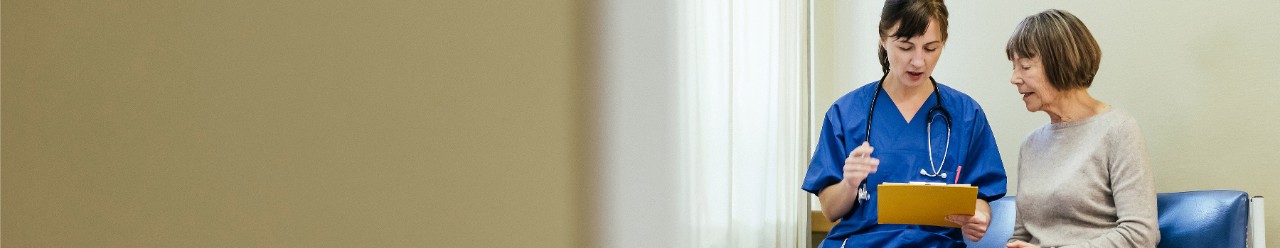  Healthcare provider looking at chart and speaking with older patient